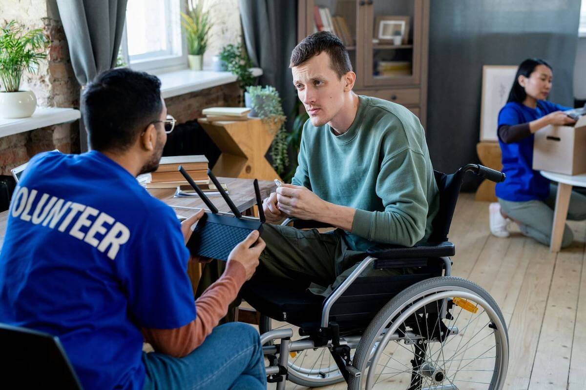 Човек с увреждане получава помощ от доброволец